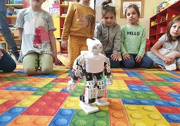 Zdjecie przedstawia grupę dzieci, które obserwują poruszanie się robota